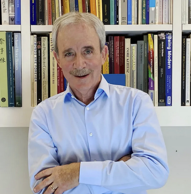 Howard Polskin, arms crossed, standing in front of a full bookcase